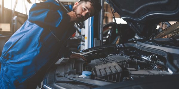 Auto mechanic with wrench over car hood. Car repairman in the service garage
